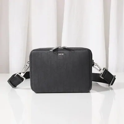 A small black boxy crossbody bag with a wide webbing strap
