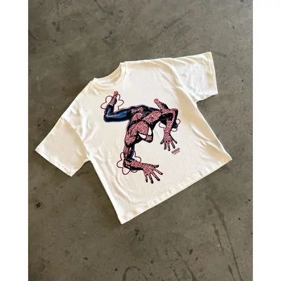 An off-white T-shirt with a printed dragon graphic, laid flat on concrete